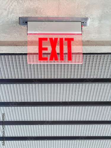 Illuminated Exit Sign Mounted on Concrete Ceiling Above Vents