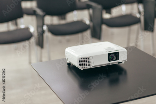 White Projector Rests On Smooth Table Surface. Closeup View Shows Professional Display Equipment In Meeting Room.