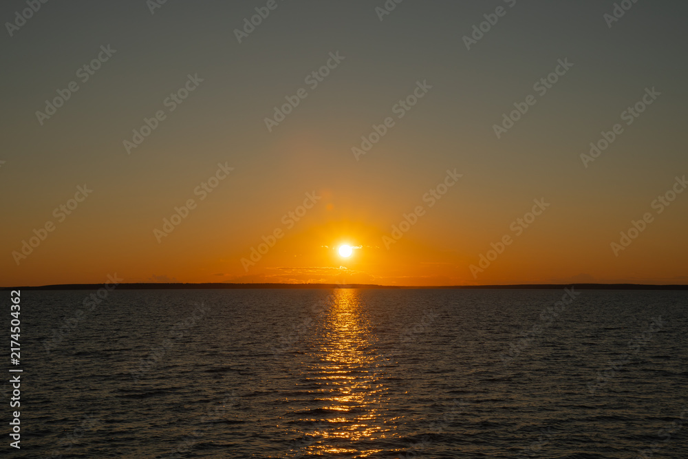 Fototapeta premium the water surface of a river or lake with sun glare at sunset
