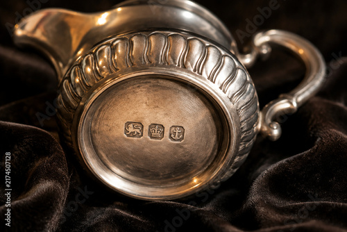 Antique silver cream jug with hallmark stamps on dark velvet, craftsmanship and heritage concept