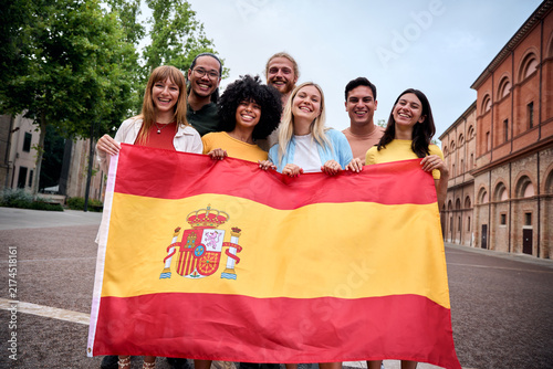 Картината върху платно Multiracial group of friends holding the Spanish flag with pride, celebrating patriotism and their passion for sports, football