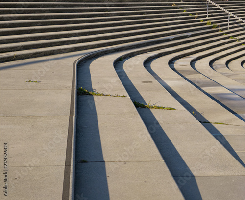 Modern concrete amphitheater steps creating abstract patterns with sunlight and deep shadows