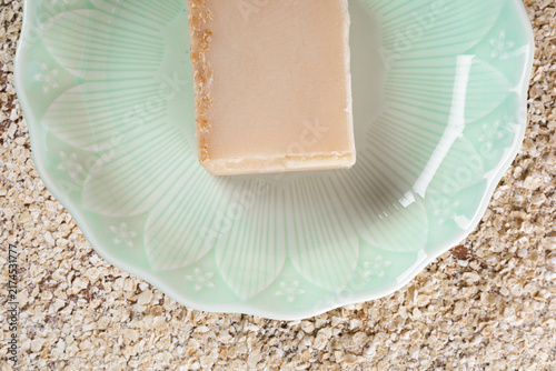 Fotografía Handmade oatmeal soap bar on green dish overhead view