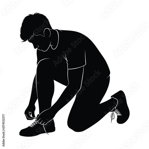 Young man kneels on the floor while tying his shoelaces in a side profile.