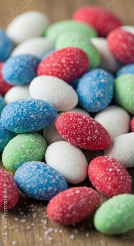 Colorful sugar coated candy eggs on wooden surface.