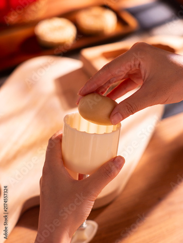 Traditional Chinese Mid‑Autumn Festival, handmade Cantonese mooncakes. Hands brush egg liquid on raw mooncake pastries, mooncakes placed on baking tray. Traditional festival food baking, folk custom, 