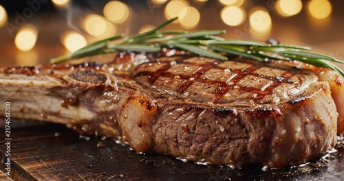 Macro shot of grilled tomahawk steak topped with fresh rosemary. Juicy, tender meat and grill marks captured in delicious detail. 4K Video 60 fps