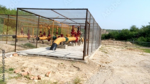 Industrial Yellow Gas Pipeline With Red Valves In Fenced Enclosure
