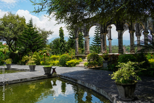 Beautiful view of the historic arched stone ruins and lush tropical gardens at Taman Ujung Water Palace in Bali, Indonesia