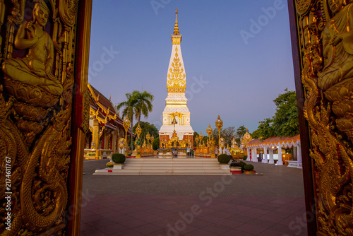 Quadro su tela Wat Phra That Phanom framed by ornate golden temple doors at twilight, famous sacred Buddhist pagoda landmark in Nakhon Phanom, Thailand