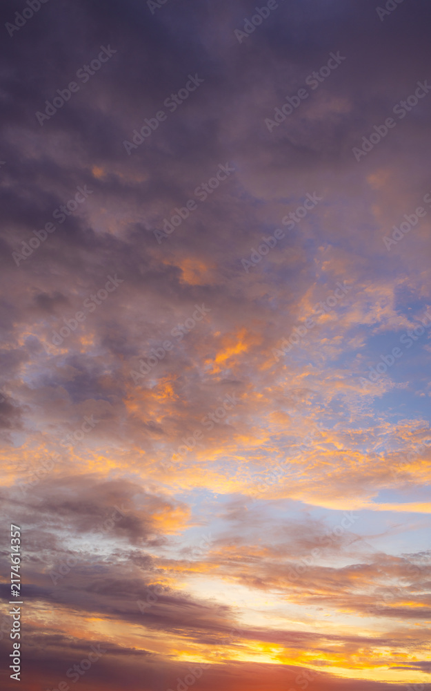 Fototapeta premium Vibrant Sunset Sky with Fiery Orange and Purple Clouds,A dramatic and colorful sunset sky filled with textured clouds. The setting sun casts intense golden-orange and warm yellow light from.