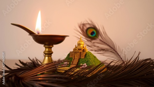 Traditional brass oil lamp with warm glow beside ornate temple miniature with captures serene close