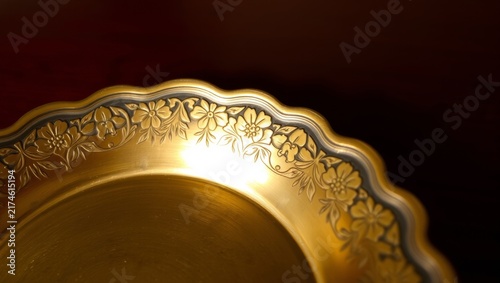 Elegant brass dish showcasing vintage floral engraved rim with warm lighting highlights with antique