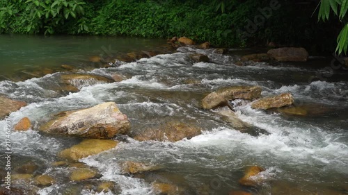 waterfall stream with rocks stones on nature clear motion flowing water by river rapids on daylight in rainy season natural forest garden or green jungle at Saraburi in Thailand for summer landscape