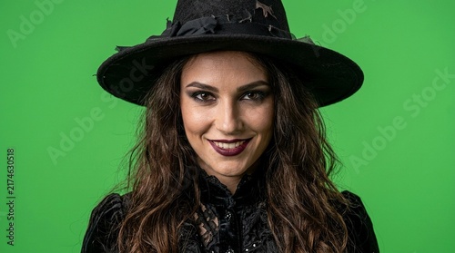 Beautiful Smiling Young Witch in Black Hat and Lace Dress Isolated on Green Screen Background