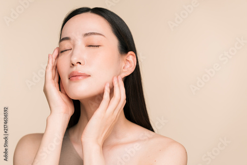 顔に手を添える黒髪ストレートヘアの若い日本人女性。スキンケアイメージ。