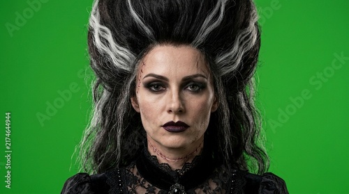 Portrait of Woman Dressed as Classic Gothic Horror Monster Bride with Scars on Green Screen Backdrop