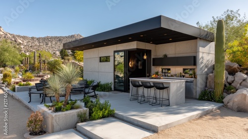 ADU + Outdoor Kitchen Modern outdoor kitchen with bar seating in a desert landscape surrounded by cacti and rocky hills.