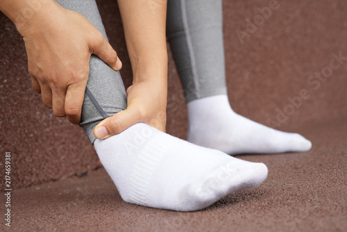 A woman with a leg ache, she is running in the park.