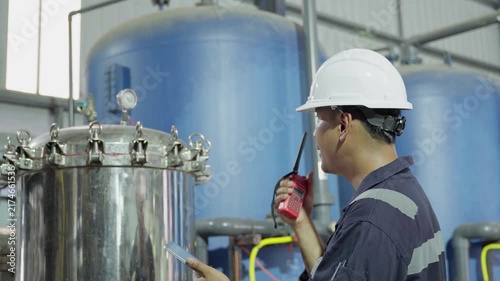 Electrical engineer is communicating with team and use radio while working on digital tablet control electrical panel in industrial plant. System PLC industrial manufacturing. Factory industry 