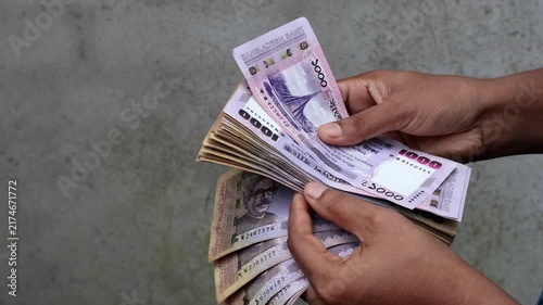 Hands Holding and Counting Stack of 1000 Bangladeshi Taka Notes - Wealth, Currency Exchange, Finance, and Business Concept