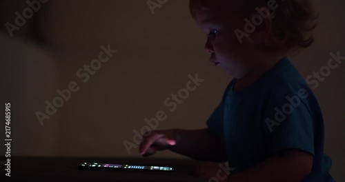 Baby pressing and  tapping with finger on phone touch screen.  Child is scrolling on mobile phone. Little child learns to use new  technologies. Baby plays with cellphone at home in the evening