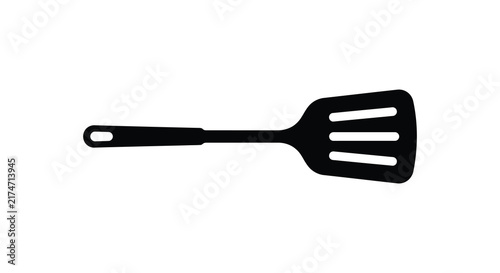 Bild auf Leinwand A black silhouette of a slotted kitchen spatula rests against a white background