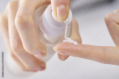 Фотография Hand dispensing skincare lotion from pump bottle onto fingertip