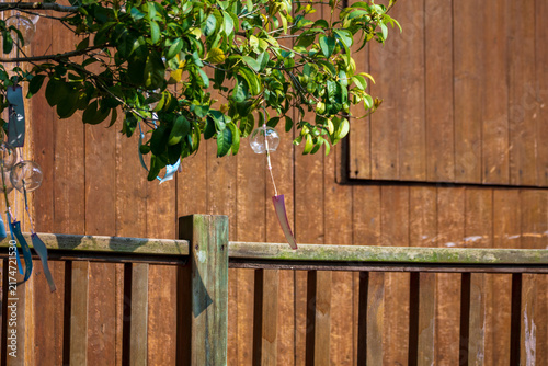 Bild auf Leinwand Backyard Garden with Wooden Fence and Hanging Wind Chimes