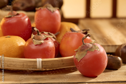 Ripe Persimmons in Bamboo Basket on Wooden Table