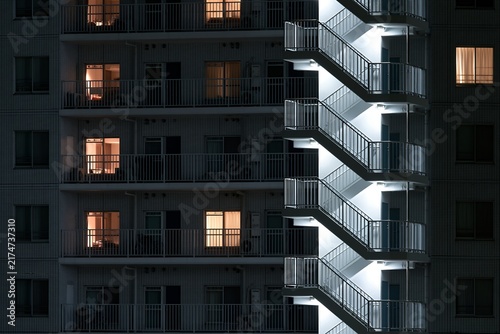 Obraz na płótnie 煌々と照らされた非常階段と窓明かりのマンション夜景