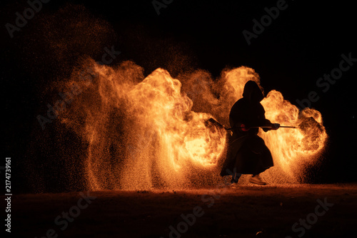 Obraz na plátně Hooded Fire Performer Spinning Flames at Night