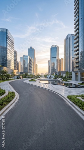 Modern city skyline with glass skyscrapers and a curving road at sunset