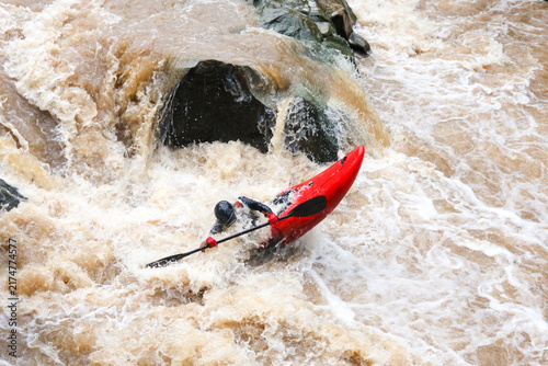 Konstfotografi Whitewater kayaker battling turbulent river rapid and foamy waterfall near dark