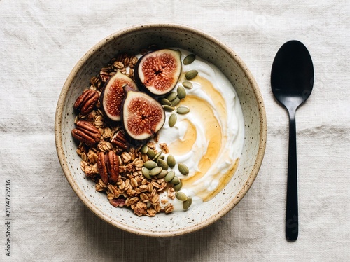Healthy autumn breakfast bowl with Greek yogurt pecan granola sliced fresh figs pumpkin seeds and honey