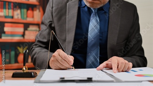 фотографія Corporate executive signing formal agreement places signature upon legal document, completing agreement workflow where signature validates official business contract agreement near desk