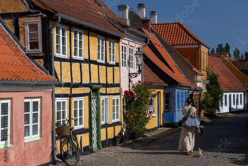 Young woman exploring picturesque half-timbered street in historic Aeroskobing alley