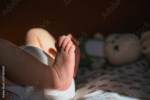 Bild auf Leinwand Newborn baby feet and toes resting in a crib, with soft morning sunlight falling