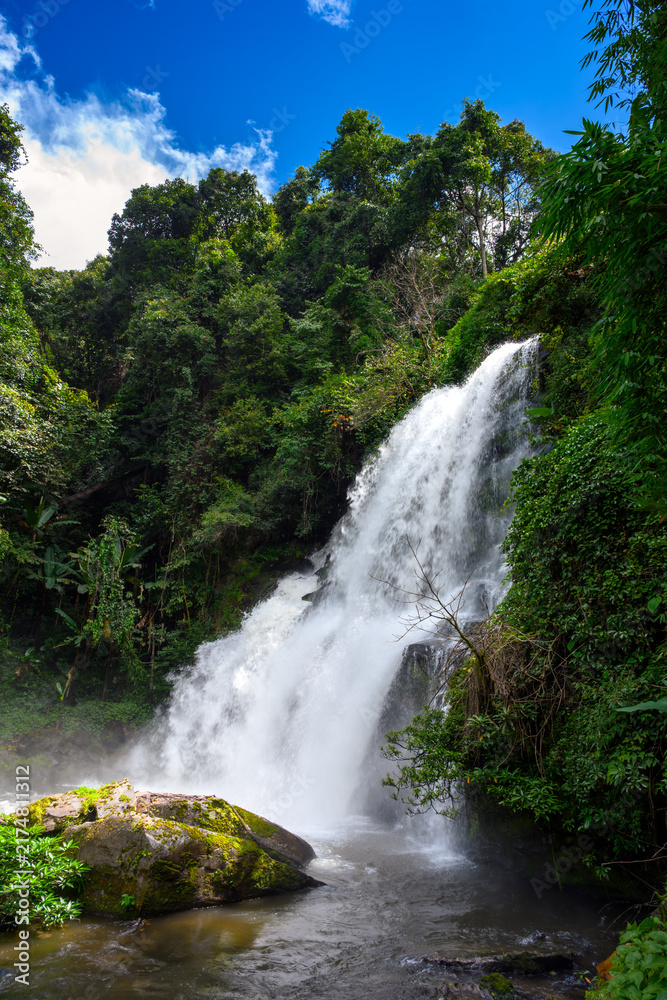 Obraz premium Pha Dok Siew waterfall cascading down steep rocks in deep lush jungle at Doi Inthanon, Chiang Mai, Thailand. Tropical rainforest nature travel concept. Vertical orientation.