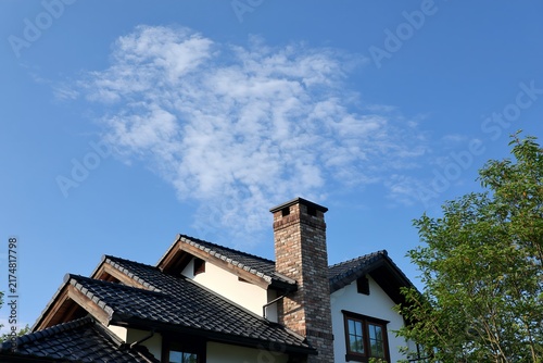 Obraz na płótnie 晴れた青空と白い雲に映える美しい洋風住宅の屋根とレンガ煙突
