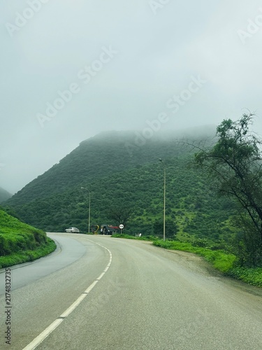 Scenic winding road through the lush green mountains of Salalah, Oman, during the Khareef season, surrounded by misty hills and breathtaking natural landscapes.  Oman infrastructure in SALALH DOFAR 
