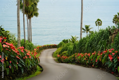 Winding tropical path surrounded by tall coconut palm trees and blooming red flowers leading to blue ocean
