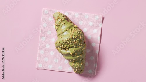 Pistachio croissant rotate on a pink polka dot napkin against a pink background, filmed from above in a clean studio setup. Fresh pastry presented in a playful  composition