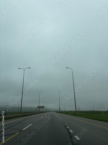 Scenic road in Salalah, Oman, winding through the lush green Dhofar Mountains during Khareef season, with misty hills, cloudy skies and beautiful natural surroundings. the gulf country near to Kerala