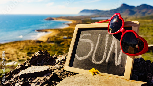 Black board with word sun against sea coast