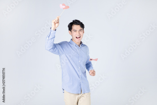 Cheerful young man holding heart props in studio