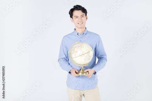 Smiling young man holding globe in studio