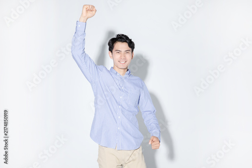 Young man cheering with raised fist and smiling in studio