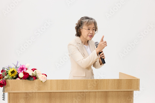 Cuadro en lienzo Senior Asian woman giving a speech at podium with microphone