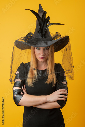 Quadro su tela Woman wearing a black witch hat with feathers and a spider decorated veil, looki